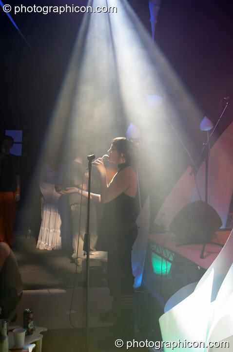 Woman vocalist illuminated by a downward cone of light in the Interdimensional Circus space at the Synergy Project. London, Great Britain. © 2005 Photographicon