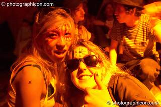 Two women with painted faces chill at The Synergy Project. London, Great Britain. © 2005 Photographicon