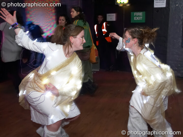 Two women wearing costumes covered in light bulbs dance at The Synergy Project. London, Great Britain. © 2007 Photographicon