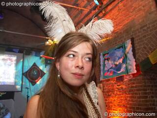 Woman with feathers in her hair takes a sideways glance at The Synergy Project. London, Great Britain. © 2007 Photographicon