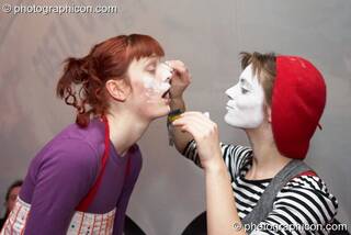 A woman white paints another woman's face at The Synergy Project. London, Great Britain. © 2007 Photographicon