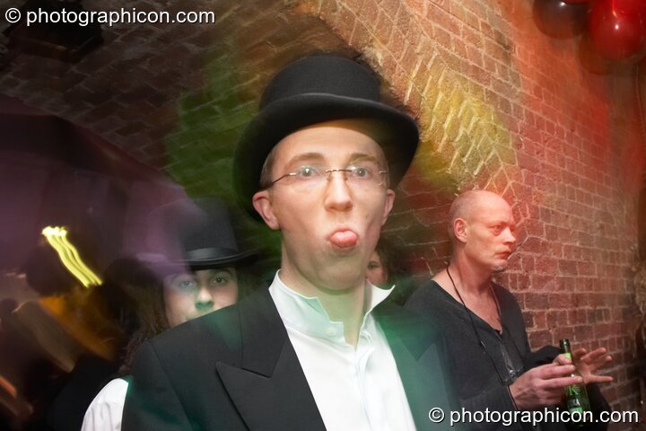 A smartly dressed man waggles his tounge in the Psycle Laughing Room at The Synergy Project. London, Great Britain. © 2007 Photographicon