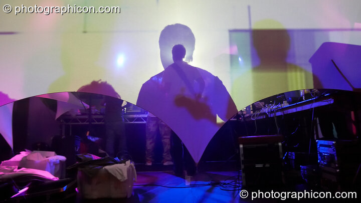 The shadows of RND aka Random (Celestial Dragon, JP/UK) viewed from behind decor fabric as they perform on the Events4Change / Nu-School Hippies stage at The Synergy Project. London, Great Britain. © 2008 Photographicon