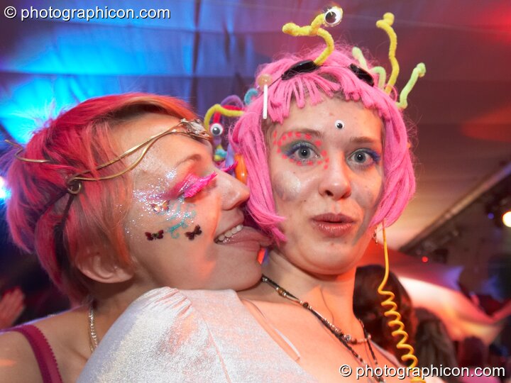 A woman wearing a pink decorated wig is kissed by another decorated lady in the Small World room at Luminopolis (formerly The Synergy Project). London, Great Britain. © 2008 Photographicon