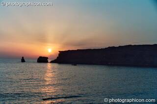 The golden sun sets over a peninsula in the sea at Agios Pavlos. Greece. © 2002 Photographicon