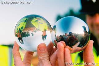 Two policeman are seen inverted through a clear plastic juggling ball, while the photographer is seen reflected in an adjacent steel juggling ball at Big Green Gathering 2003. Cheddar, Great Britain. © 2003 Photographicon