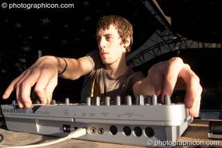 In pre-sunset shadows, the long arms of Matt Allaby (Nano Records) coax big sounds from a midi controller on the Origin Stage at Glade Festival 2007. Aldermaston, Great Britain. © 2007 Photographicon