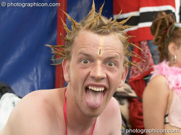 Man with spiky hair pulls a face in response to the mud at Glastonbury Festival 2005. Pilton, Great Britain. © 2005 Photographicon