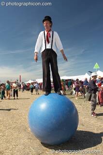 A man stands balanced on top of a large inflateable ball at Sunrise Celebration 2007. Yeovil, Great Britain. © 2007 Photographicon