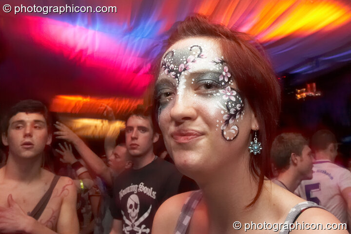 A woman with enigmatic expression and painted face dances to an illuminated backdrop in the Mistzfiedmind space at The Synergy Project. London, Great Britain. © 2007 Photographicon