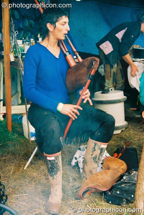 Woman plays a bagbipe by the fireside at Big Green Gathering 2003. Cheddar, United Kingdom. © 2003 Photographicon