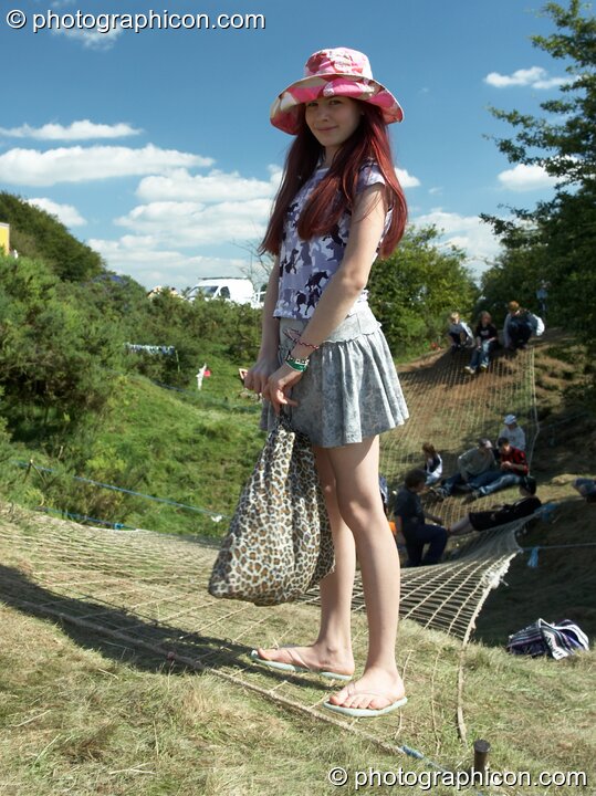 Girl stands on webbing bridge at Big Green Gathering 2005. Burrington, Cheddar, United Kingdom. © 2005 Photographicon