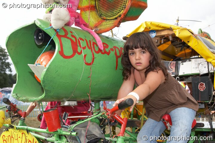 A young girl sitting on the Rinky-Dink mobile pedal-powered sound-system at Big Green Gathering 2006. Burrington, Cheddar, United Kingdom. © 2006 Photographicon