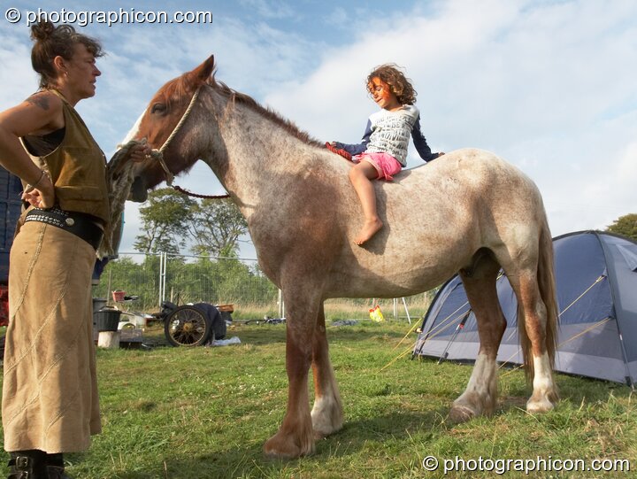 A small girl sitting on horse back in the Horse-drawn Camp at Big Green Gathering 2006. Burrington, Cheddar, United Kingdom. © 2006 Photographicon