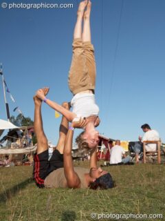A man lies on his back supporting a woman practicing acrobatics at Big Green Gathering 2007. Burrington, Cheddar, United Kingdom. © 2007 Photographicon