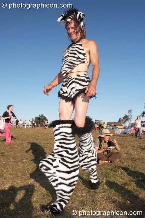 A man in zebra-striped loincloth and leggings strolls past at Big Green Gathering 2007. Burrington, Cheddar, United Kingdom. © 2007 Photographicon