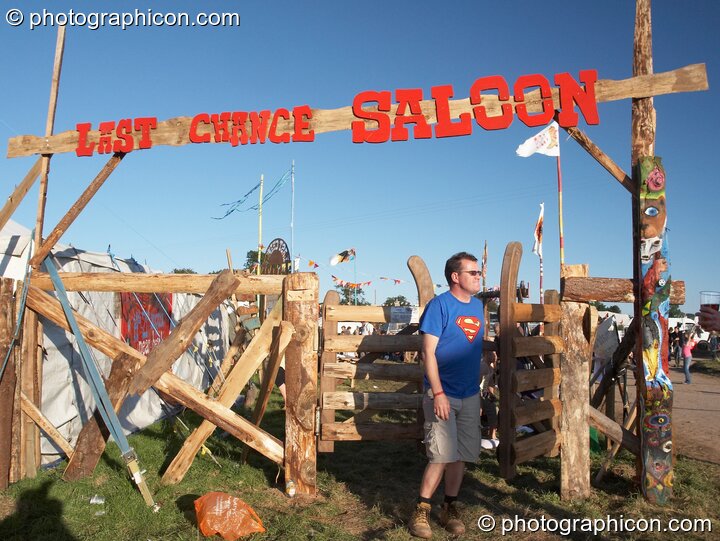 A man leaves through the swinging wooden gates outside the Last Chance Saloon at Big Green Gathering 2007. Burrington, Cheddar, United Kingdom. © 2007 Photographicon