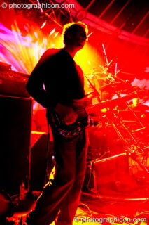 Chris Taylor (guitarist) of The Bays silhouetted against red and yellow lights while performing on the Main Stage at Glade Festival 2005. Aldermaston, United Kingdom. © 2005 Photographicon