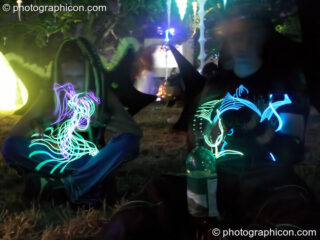A couple play with flashing electo-luminescent fibres by night in the idpiral chillout at Glade Festival 2005. Aldermaston, United Kingdom. © 2005 Photographicon