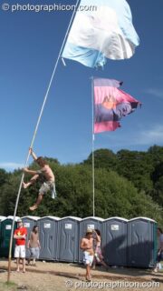 Man climbs large flag pole at Glade Festival 2005. Aldermaston, United Kingdom. © 2005 Photographicon