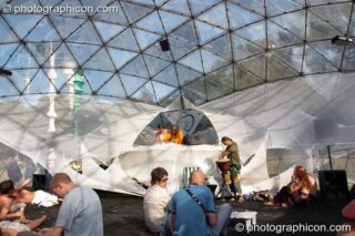 A distant wide shot of Red Earth DJing in the IDSpiral transparent geodesic dome on a bright blue day at Glade Festival 2006. Aldermaston, United Kingdom. © 2006 Photographicon