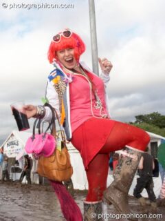 A woman dressed in pink swings on a pole while swigging a pint in the mud at Glade Festival 2007. Aldermaston, United Kingdom. © 2007 Photographicon