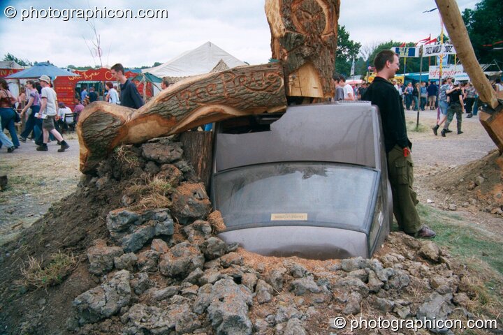 Tree Pirates chainsaw sculpture of a tree burying a car at Glastonbury Festival 2002. Pilton, United Kingdom. © 2002 Photographicon