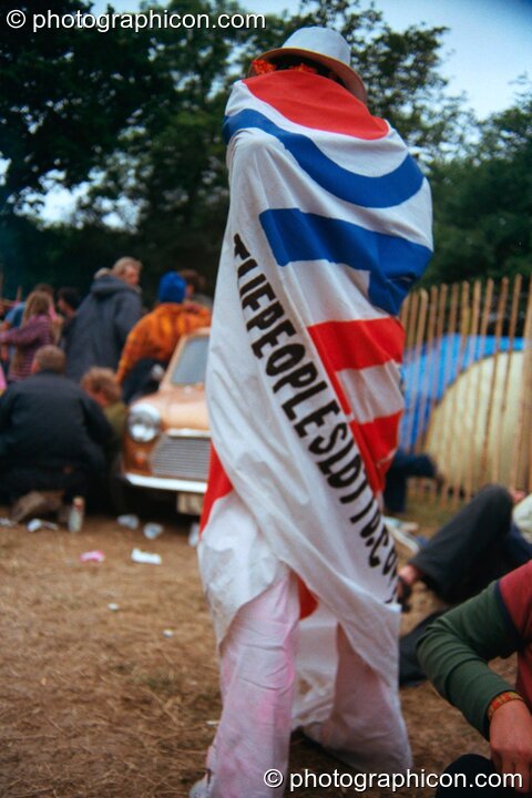 Woman wrapped in large banner for the Peoples Lotto in the Lost Vaguess field at Glastonbury Festival 2002. Pilton, United Kingdom. © 2002 Photographicon