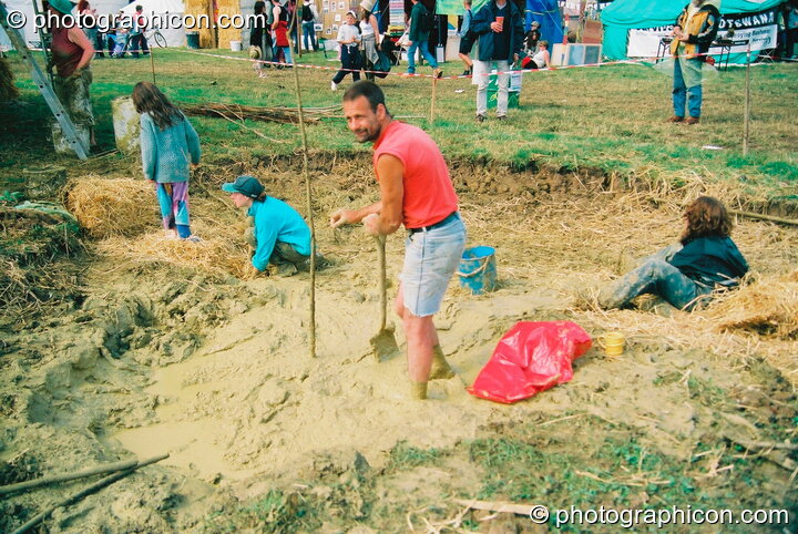 Man digging mud to build a large sculpture of a rhino in the Green Futures field at Glastonbury Festival 2003. Pilton, United Kingdom. © 2003 Photographicon
