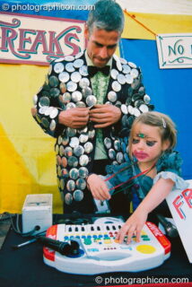 Man and daughter play music for the freak show in the Lost Vagueness field at Glastonbury Festival 2003. Pilton, United Kingdom. © 2003 Photographicon