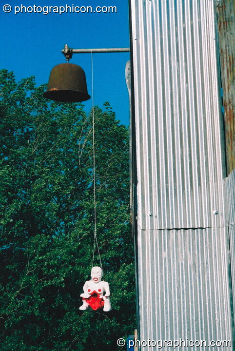 A figurine hanging over the entrance to the chapel in the Lost Vagueness field at Glastonbury Festival 2003. Pilton, United Kingdom. © 2003 Photographicon