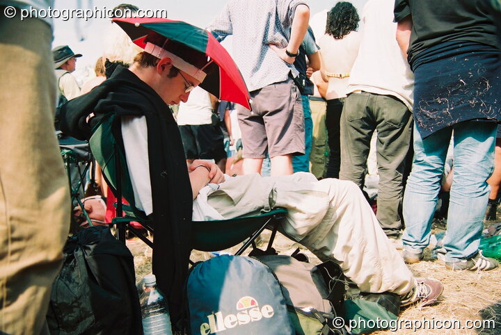 Man with sunhat sleeps through a performance of Yes at Glastonbury Festival 2003. Pilton, United Kingdom. © 2003 Photographicon