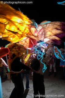 Two people wearing illuminated costumes with large heads and arms embrace at Glastonbury Festival 2004. Pilton, United Kingdom. © 2004 Photographicon