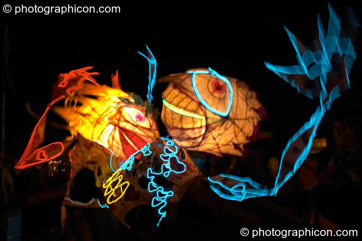 Two people wearing illuminated costumes with large heads and arms embrace at Glastonbury Festival 2004. Pilton, United Kingdom. © 2004 Photographicon