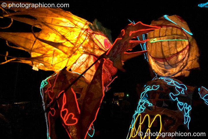 Two people wearing illuminated costumes with large heads and arms embrace at Glastonbury Festival 2004. Pilton, United Kingdom. © 2004 Photographicon