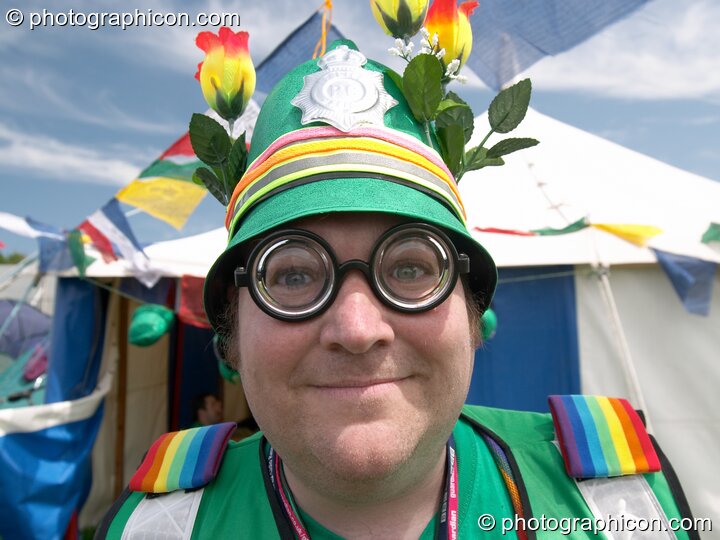 Green Policeman with thick glasses and flowers on his helmet at Glastonbury Festival 2005. Pilton, United Kingdom. © 2005 Photographicon
