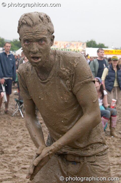 Man wearing a T-shirt is covered head to foot in mud at Glastonbury Festival 2005. Pilton, United Kingdom. © 2005 Photographicon