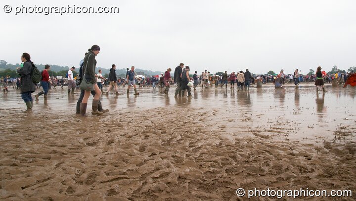People walking through a lake of mud around the Other Stage at Glastonbury Festival 2005. Pilton, United Kingdom. © 2005 Photographicon