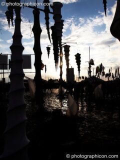The sun reflects off the mud, silhouetting hanging decor in the ID Spiral arena of the Dance Village at Glastonbury Festival 2007. Pilton, United Kingdom. © 2007 Photographicon