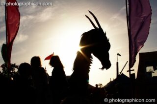 Silhouetted against the setting sun, children play on a dragon sculpture in the Green Roadshow Field at Glastonbury Festival 2008. Pilton, United Kingdom. © 2008 Photographicon