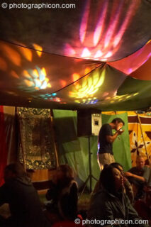 A man lights a cigarette beneath decor and lighting show in the Progressive Tent at Planet Bob's Offworld Festival 2007. Swindon, United Kingdom. © 2007 Photographicon