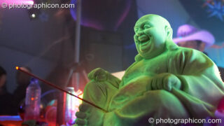 A plastic Buddha with phallic incense stick on the Main Stage at Planet Bob's Offworld Festival 2007. Swindon, United Kingdom. © 2007 Photographicon