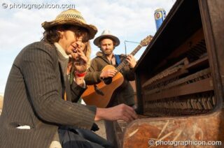 A group of friends jam on a wonky piano in the early morning mud at the Secret Garden Party 2007. Huntingdon, United Kingdom. © 2007 Photographicon