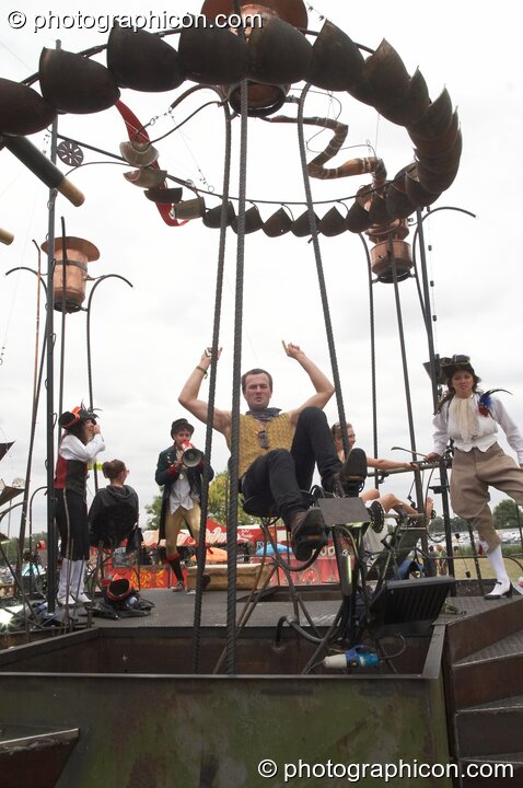 A man pedal-powers the metal sculpture by Circus Kinetica that pumps French Revolution Courvoisier to a bar at the Secret Garden Party 2010. Huntingdon, United Kingdom. © 2010 Photographicon