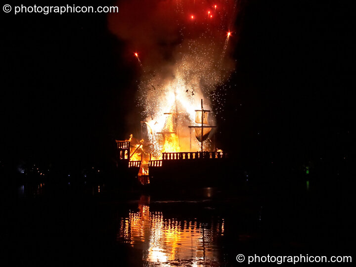 Fireworks erupt aboard the burning Galleon ship on the lake at the Secret Garden Party 2008. Huntingdon, United Kingdom. © 2008 Photographicon