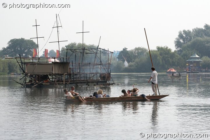 A punt makes an early morning trip to the burned out Galleon ship on the lake at the Secret Garden Party 2008. Huntingdon, United Kingdom. © 2008 Photographicon