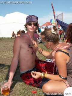 A woman paints a man's chest while chilling in the ID Spiral Arena at Sunrise Celebration 2007. Yeovil, United Kingdom. © 2007 Photographicon