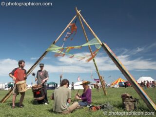 The Mordekkers jam some music in the sun under a wooden pyramid frame at Sunrise Celebration 2007. Yeovil, United Kingdom. © 2007 Photographicon