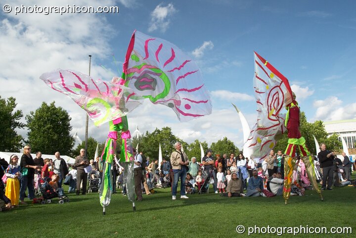 Women wearing bright winged costumes gracefully dance on stilts at the Thames Festival 2004. London, United Kingdom. © 2004 Photographicon