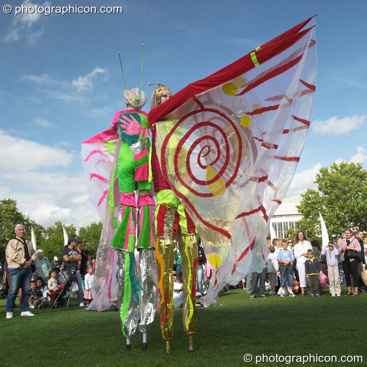 Women wearing bright winged costumes gracefully dance on stilts at the Thames Festival 2004. London, United Kingdom. © 2004 Photographicon